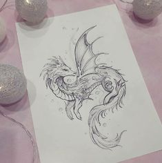 a drawing of a dragon on a sheet of paper next to some balls and lights