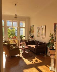 a living room filled with lots of furniture next to two large windows and potted plants