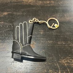 a black boot keychain with a gold chain hanging from it's side