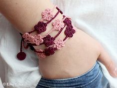 a close up of a person's arm wearing a bracelet with crocheted flowers