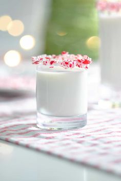 a close up of a drink in a glass with candy canes on the rim