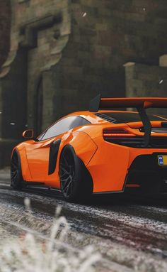 an orange sports car parked on the side of a road next to a brick building