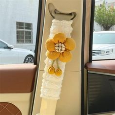 a car door handle decorated with yellow flowers and white ruffles, hanging from it's side