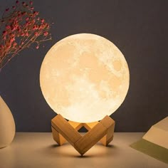 the moon lamp is sitting next to a vase with flowers in it on a table