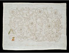 an embroidered piece with flowers and vines on it's side, in white linen