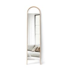 a large mirror sitting on top of a white wall next to a couch in front of a window