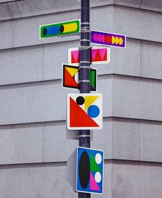 a pole with several street signs attached to it's sides on the side of a building