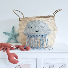 a basket with a jellyfish on it sitting on top of a white dresser next to a starfish