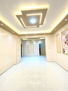 an empty room with white walls and flooring is lit by recessed light fixtures