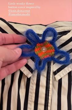 someone is stitching an orange and blue flower on top of a black and white striped shirt