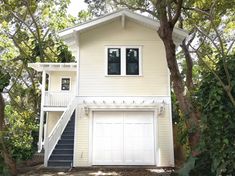 a two story white house with stairs leading up to it