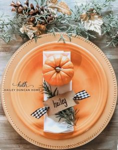 an orange plate topped with two small pumpkins on top of a wooden table next to pine cones