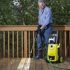 an older man is cleaning the deck with a pressure washer and yellow vacuum cleaner