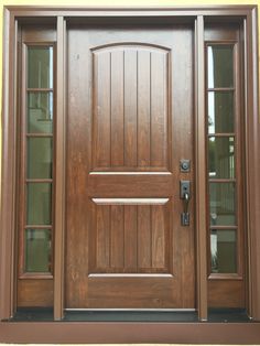 a wooden door with two sidelights and glass panels on the front of a house