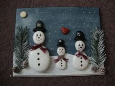 three snowmen standing next to each other on top of a tile covered in snow