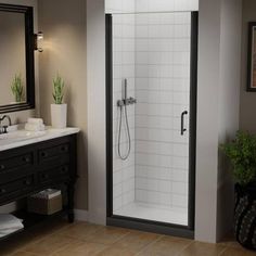 a bathroom with a walk in shower next to a white sink and black vanity mirror