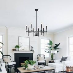 a living room filled with furniture and a fire place under a chandelier in front of a fireplace