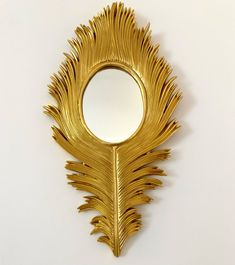 a mirror that is shaped like a gold peacock's tail on a white wall