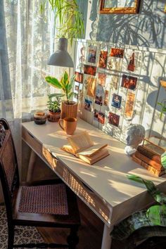 a desk with some plants and pictures on the wall next to it in front of a window