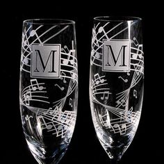 two wine glasses with musical notes and the letter m on each glass, one is filled with water