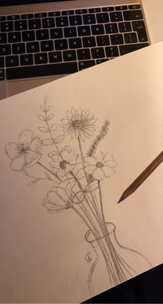 a drawing of flowers in a vase next to a laptop