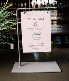 there is a sign that says cocktails on the table next to a potted plant