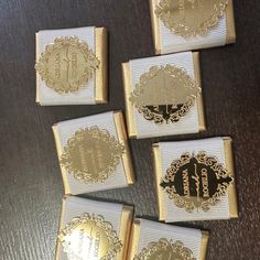 four gold and white boxes with monogrammed labels on them sitting on a table