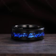 a black ring with blue flames inlaying the center on a wooden table top