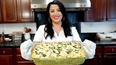 a woman holding up a casserole dish in the kitchen