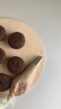 four cookies on a wooden plate with a knife next to it and a bag of chips