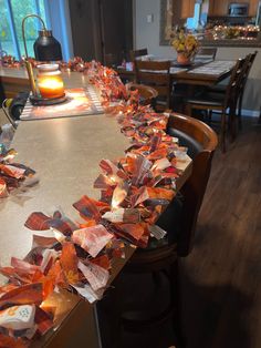 the table is covered with many pieces of orange tissue paper and lit candles on it