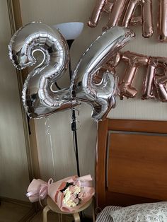 two balloons that say happy 25th and are in front of a bed with flowers on it