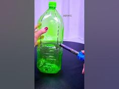 a person is painting a green plastic bottle