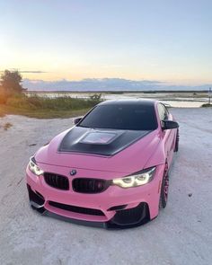 a pink car parked on top of a sandy beach