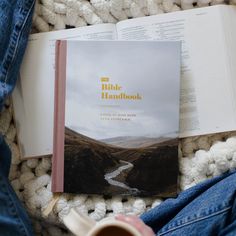 the bible handbook is open on a blanket with a cup of coffee next to it