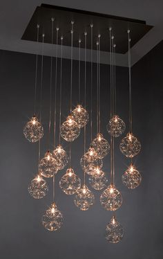 a chandelier hanging from the ceiling in a room with grey walls and flooring