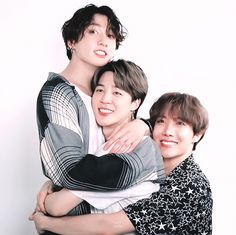 three young men hugging each other in front of a white background