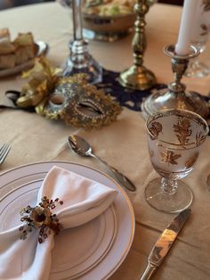 the table is set with silverware and white napkins, gold - plated utensils