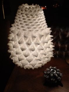 a large white vase sitting on top of a wooden table next to a pine cone