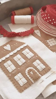 the gingerbread house is made out of brown paper and white fabric, along with some spools of twine