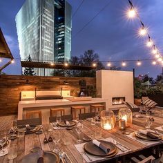 an outdoor dining area is lit up with string lights and place settings on the table