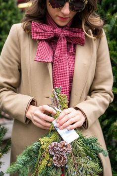 a woman wearing sunglasses and a coat holding a christmas wreath