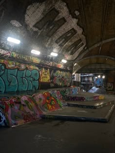 an indoor skate park with graffiti on the walls