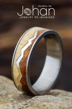 a wedding ring with wood inlays on top of a stone slab, and the words johan jewelry re - imagine