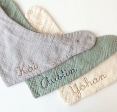 three bibs with names on them sitting next to each other in different colors and sizes