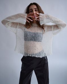 a woman is posing with her hands on her head and wearing a sweater over her shoulders