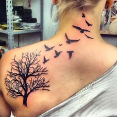 a woman with a tree and birds tattoo on her upper back neck, which is covered in black ink