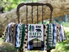 a wooden chair with a sign that says one happy camper hanging from it's back