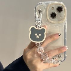 a person holding up a phone case with a cat keychain attached to it