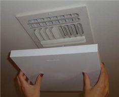 a person is holding up an air vent in the ceiling